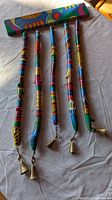 Full view of wind chime hanging to show painted wood tubes and brass bells