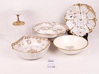 Group shot of five white ceramic pieces with gold accents