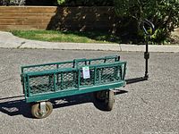 Full view of green foldable garden cart upright on pavement