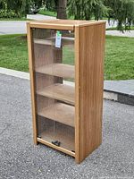Front view of oak stereo cabinet showing glass door and shelves