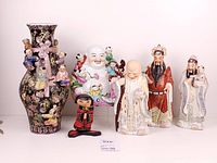 Group shot of vase, laughing Buddha, three wise men, and small doll