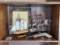 Shelf view showing both model ships, plaque and toy gun