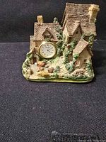 Front view of resin cottage clock showing entire piece and dial
