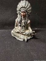 Front view of seated Native American chief figurine holding peace pipe