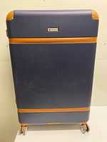 Front view of navy suitcase with tan trim and spinner wheels
