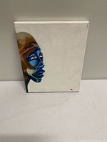 Front view of painting showing blue-toned face on white background