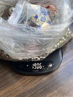 Whole bag of jewelry on digital scale showing 1906 g