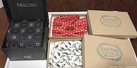 Overview of all boxed accessories: Fascino tie box open showing tie, two Little Gents boxes with bow ties visible
