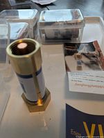 Close-up of one brass freeze protection unit standing upright with packaging in background