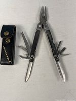 Multitool open displaying pliers and various blades alongside sheath