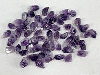 Group of approximately fifty rough amethyst pieces on white background