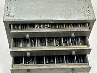 Overall view of open three-drawer cabinet with drill bits visible in compartments