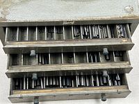 Overall view of cabinet with three drawers partially open showing drill bits