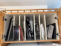 Cabinet showing multiple bakeware pieces separated in vertical dividers