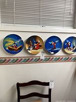Four Mickey Mouse collector plates on wall