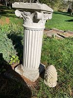 Full view of pillar and pine cone on ground