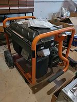 Three-quarter view of generator showing frame, wheels, engine, and manuals on tank