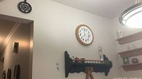 Overall wall showing clock, shelf, Galileo thermometer, apple shakers, and one trivet