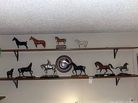 Shelf overview showing nine horse figurines and central plate