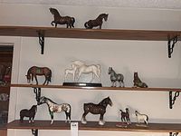 All twelve ceramic horse figurines displayed on three shelves