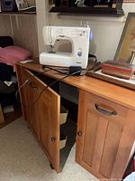 Kenmore sewing machine on top of wood cabinet with doors open