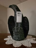 Front view of carved stone eagle statue with MaxSold lot tag visible