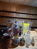 Group view of assorted glass and ceramic vases, tankard mug visible front left