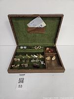 Open wooden jewellery box with cufflinks and tie clips displayed
