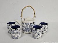 Front view of teapot with cups displaying floral pattern