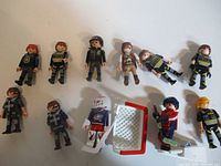 Group of 11 Playmobil figures with accessories laid out on white surface