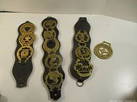 Overview of three leather straps with brass brasses and one loose brass