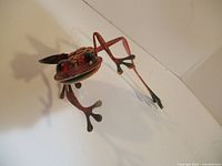Front angled view of painted metal frog figurine