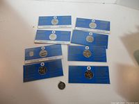 Group of seven blue-carded coins and loose medallion