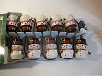 Full view of all ten snowman lights connected on cord inside box