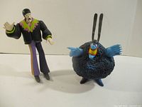 John Lennon and Blue Meanie figures standing side by side