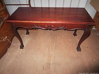Closed mahogany piano bench showing carved apron and ball-and-claw legs