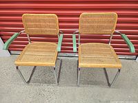 Front view of both Marcel Breuer Cesca chairs showing cane seats, backs, chrome frames, green armrests