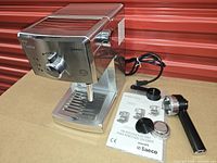 Front angled view showing machine, portafilter, baskets, scoop and manual