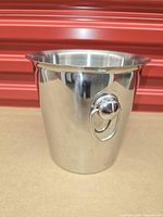 Front view of stainless steel ice bucket showing one ring handle and polished finish