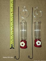Two feeders, hanging rods and swirl hooks beside tape measure for scale