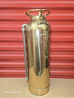 Full view of brass fire extinguisher standing upright