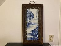 Full view of framed blue and white porcelain plaque standing upright