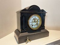 Front three-quarter view of Ansonia mantel clock with key resting at base