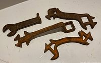 Overview of four rusted cast iron farm implement wrenches on flat surface
