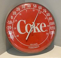Front view of red Coca-Cola 12" thermometer showing dial and pointer