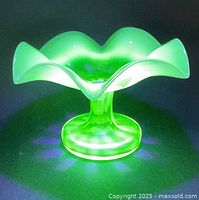 Top-front view showing glowing green uranium glass dish under UV light