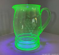 Full view of uranium glass pitcher glowing under UV