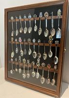 Front view of cabinet showing four rows of souvenir spoons