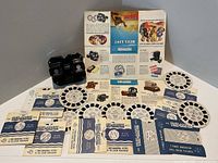 Group shot showing viewer, thirteen reels with sleeves and brochure