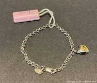 Bracelet laid flat showing chain, heart charm, 925 tag and lobster clasp